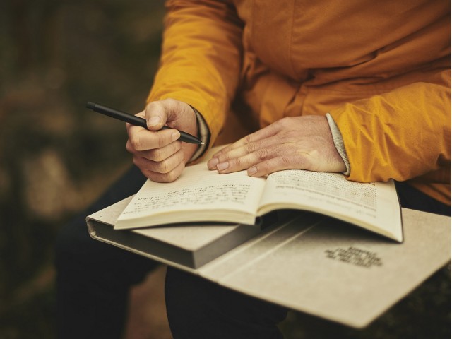 odrasla oseba piše v knjigo